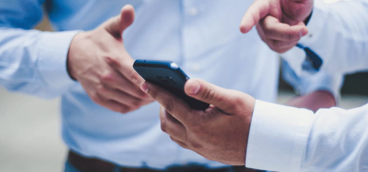 two men looking at mobile phone pointing