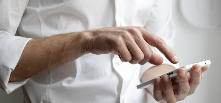 man in white shirt using mobile phone in hand