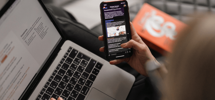 person using mobile phone while also on laptop