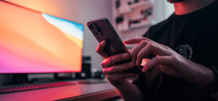 man in front of monitor using mobile phone in black shirt