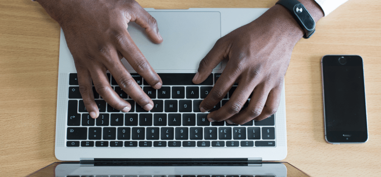 man working on laptop with smartphone
